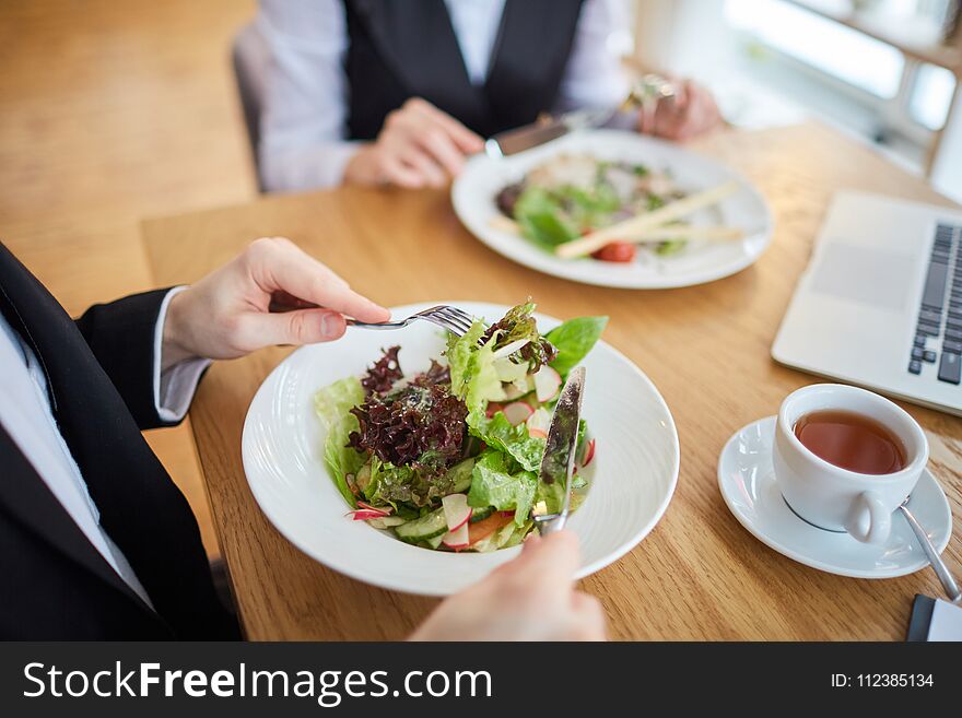 Close-up of business people eating salad at restaurant