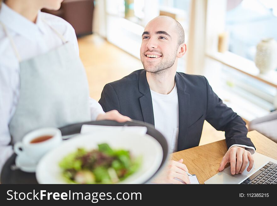 Smiling man using his laptop at restaurant. Smiling man using his laptop at restaurant