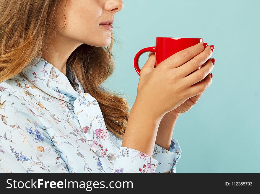 Young pretty woman holding a cup of tea or coffee over blue background