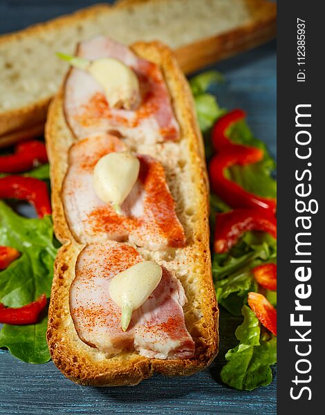 Sandwich with bacon and vegetables on blue wood background