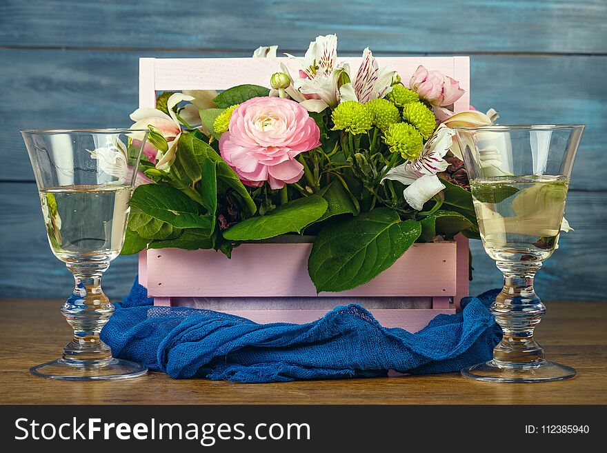 Arrangement with flowers in a pink wooden box and wine