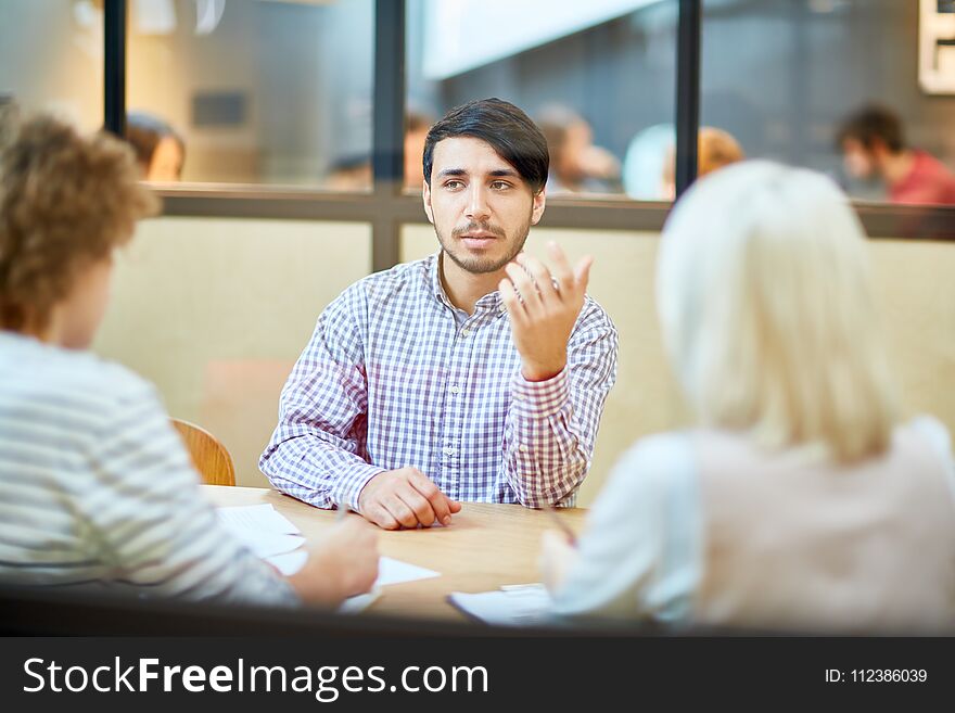 Young applicant explaining his objectives while talking to employers during interview in office. Young applicant explaining his objectives while talking to employers during interview in office