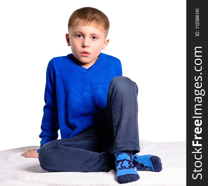 A boy in a blue jacket sits, isolated on a white background