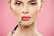 Beauty Concept - Woman Applying Red Lipstick With Pink Studio Background. Beautiful Girl Makes Makeup. Stock Images