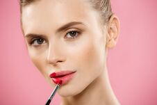 Beauty Concept - Woman Applying Red Lipstick With Pink Studio Background. Beautiful Girl Makes Makeup. Royalty Free Stock Photography