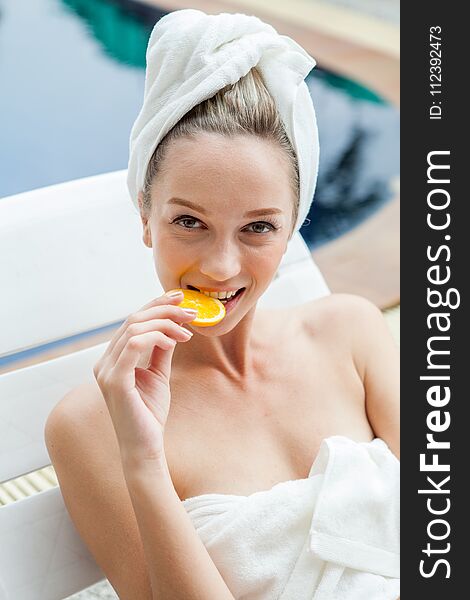 Beautiful young woman bite orange slices with a towel wrapped around head