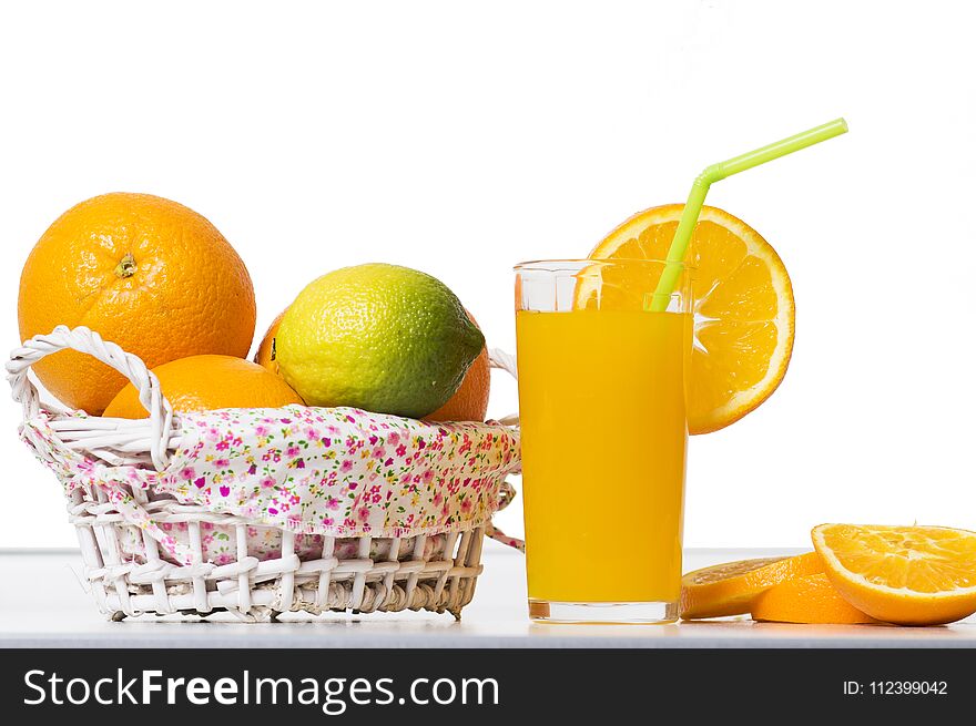 Fresh orange juice in a glass beaker, slices of sliced oranges and basket on table isolated on white background