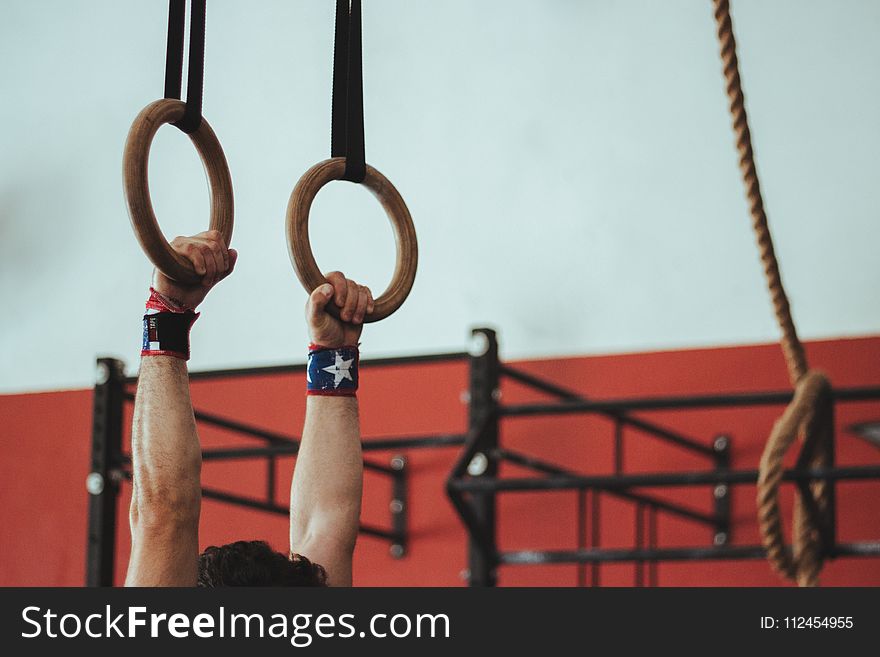 Male Gymnast Holding On To Two Wooden Rings