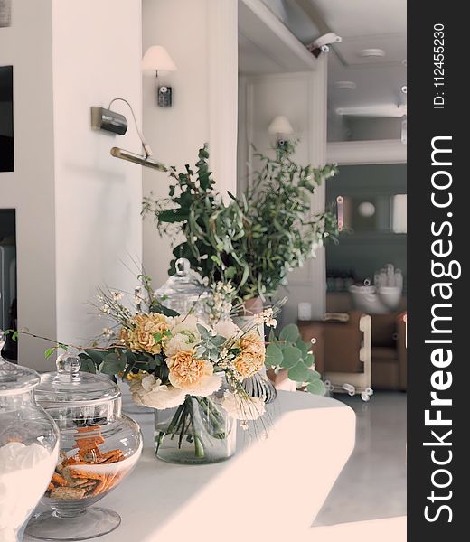 White And Yellow Petaled Flowers Centerpiece Near Clear Glass Jars On Top Of White Wooden Table