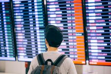 Young Male Traveler Watching And Waiting For Flight Time Schedule On Boarding Time Monitor Screen. Royalty Free Stock Photography