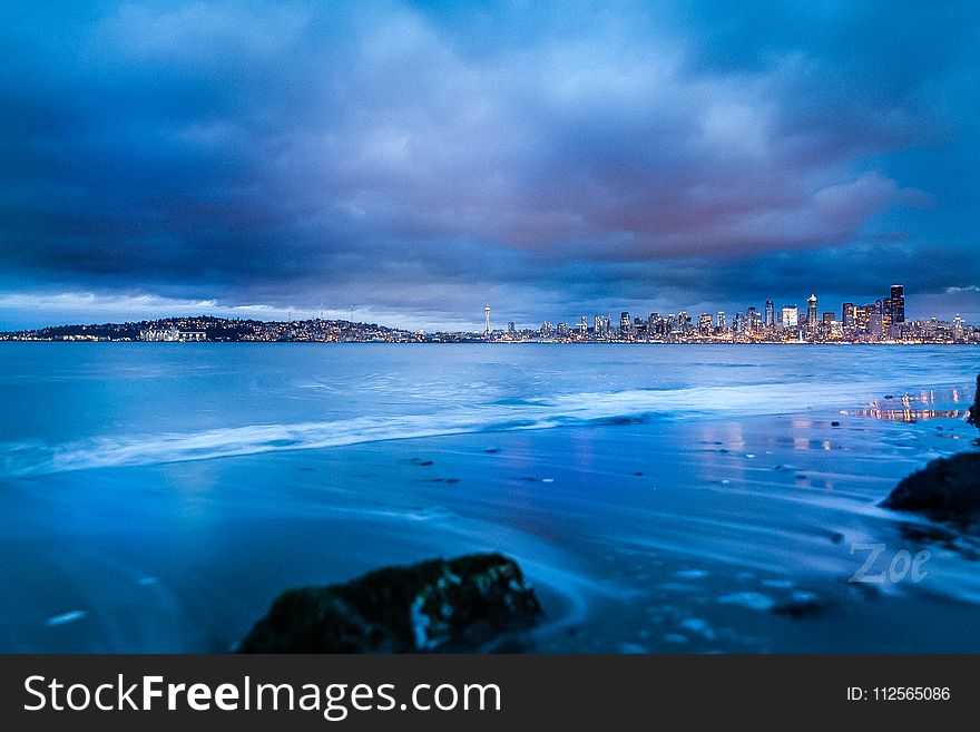 City Buildings Near Body of Water Under Gray Clouds