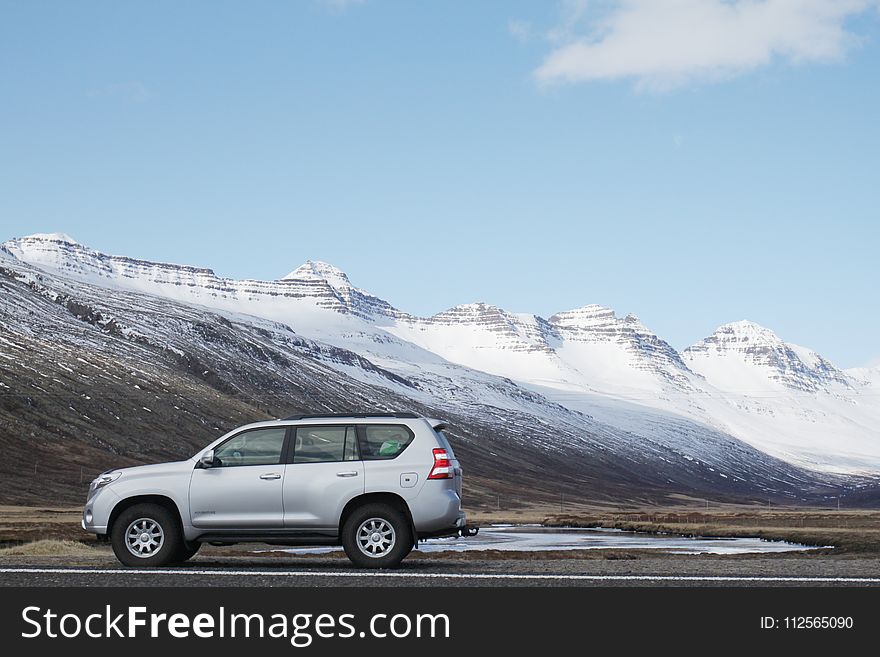 Gray Sports Utility Vehicle on Road Near Snow Covered Mountain