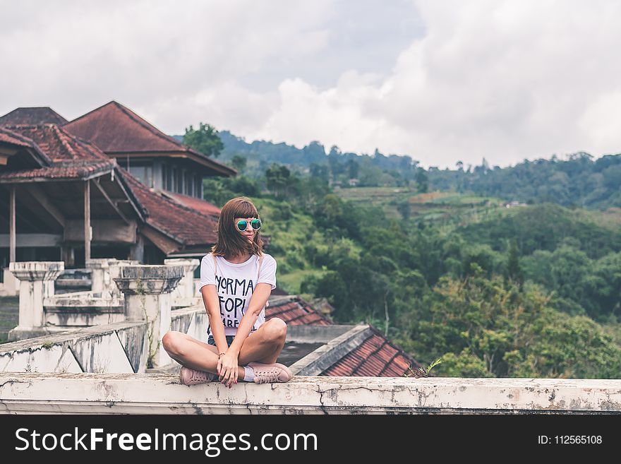 Photo of Woman Sitting on Concrete Balustrade