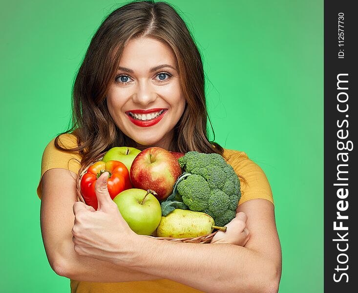 Young smiling woman holding straw basket with fruits and vegetables.