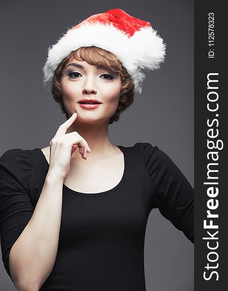 model wearing in black dres. Santa girl portrait with Christmas hat. Studio portrait.