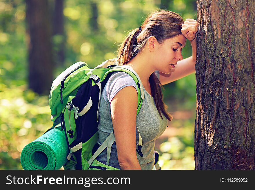 Tired woman hiking tourist resting near tree.