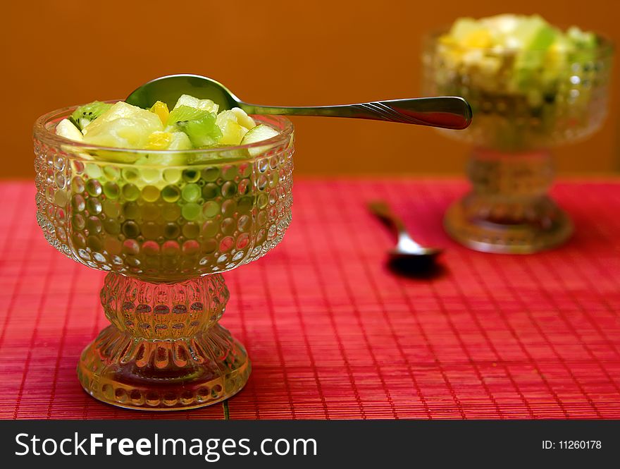 Two ice-cream bowls with fruit salad and spoons. Two ice-cream bowls with fruit salad and spoons