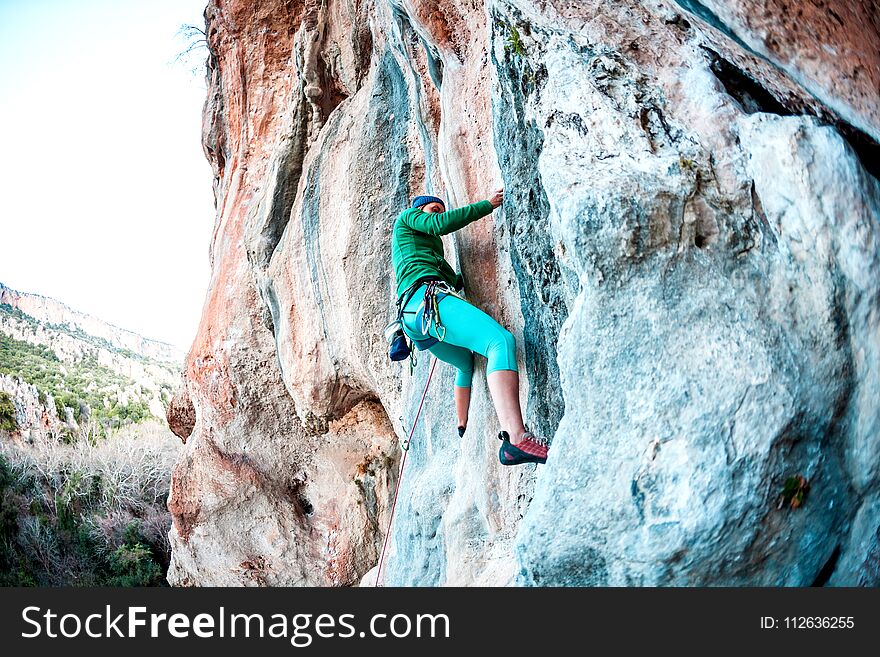A woman climbs the rock. Climbing in nature. Fitness outdoors. Active lifestyle. Extreme sports. The athlete trains on a natural relief.