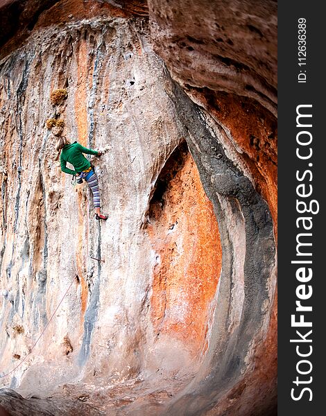 A woman climbs the rock. Climbing in nature. Fitness outdoors. Active lifestyle. Extreme sports. The athlete trains on a natural relief.