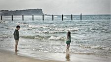Two Young Children Standing On The Beach Watching The Waves Royalty Free Stock Photo