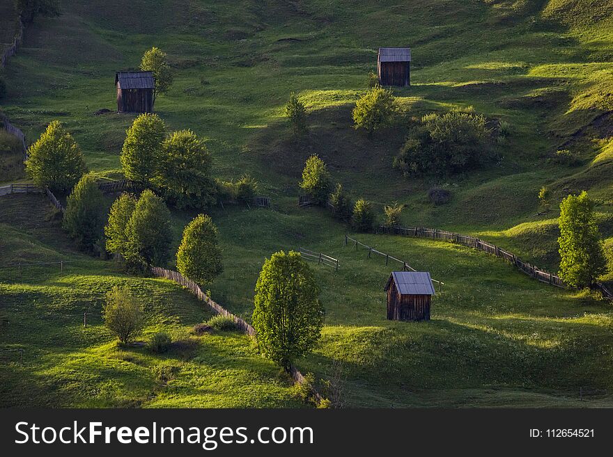 Cottages On A Green Field In The Rural Countryside Of Romania