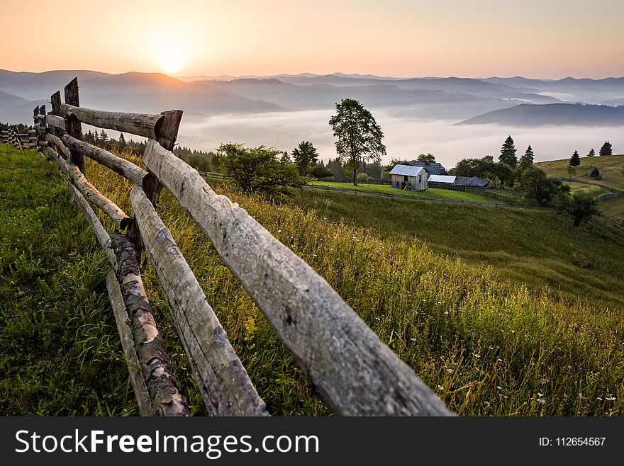 Wooden fence leading to a distant village in the countryside of Romania. Wooden fence leading to a distant village in the countryside of Romania