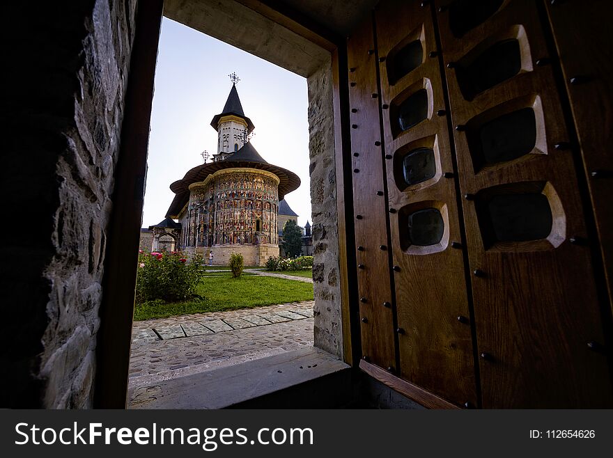 Painted church monastery of Bucovina region in Romania seen through a doorway. Painted church monastery of Bucovina region in Romania seen through a doorway