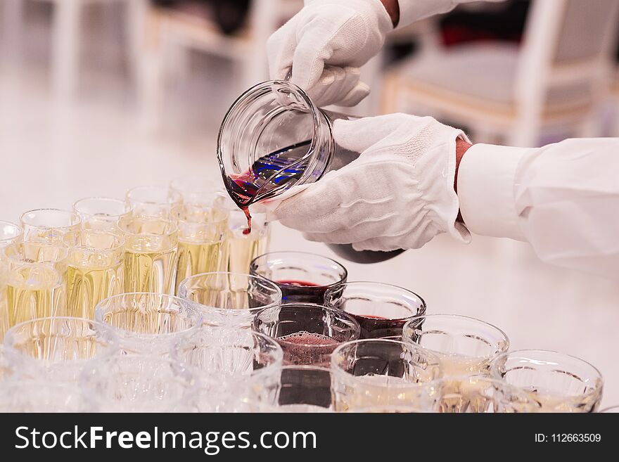 The waiter pours drink fruit drink in glasses. Service at restaurant