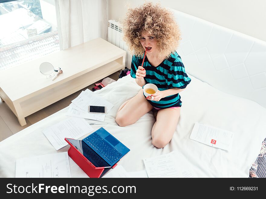 Woman working on her bed with laptop