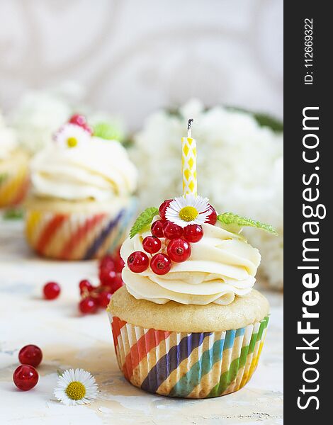 Gentle cupcake with cream and berries nd a candle a light background.