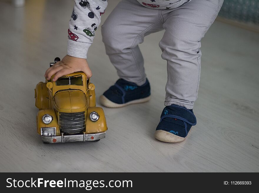 Little Boy Playing On The Ground With Yellow Car At Home