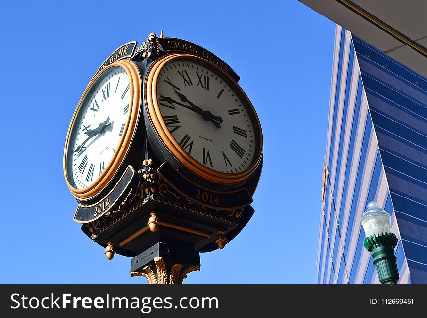 Close-up Photo of Street Clock Near Tall Building