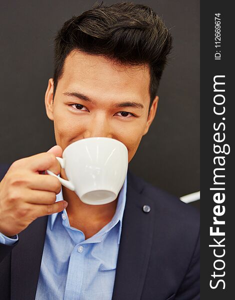 Asian man enjoys break and drinks coffee in the officee