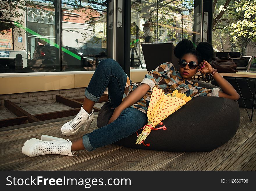 Woman Lying on Black Bean Bag Chair Near Cafe