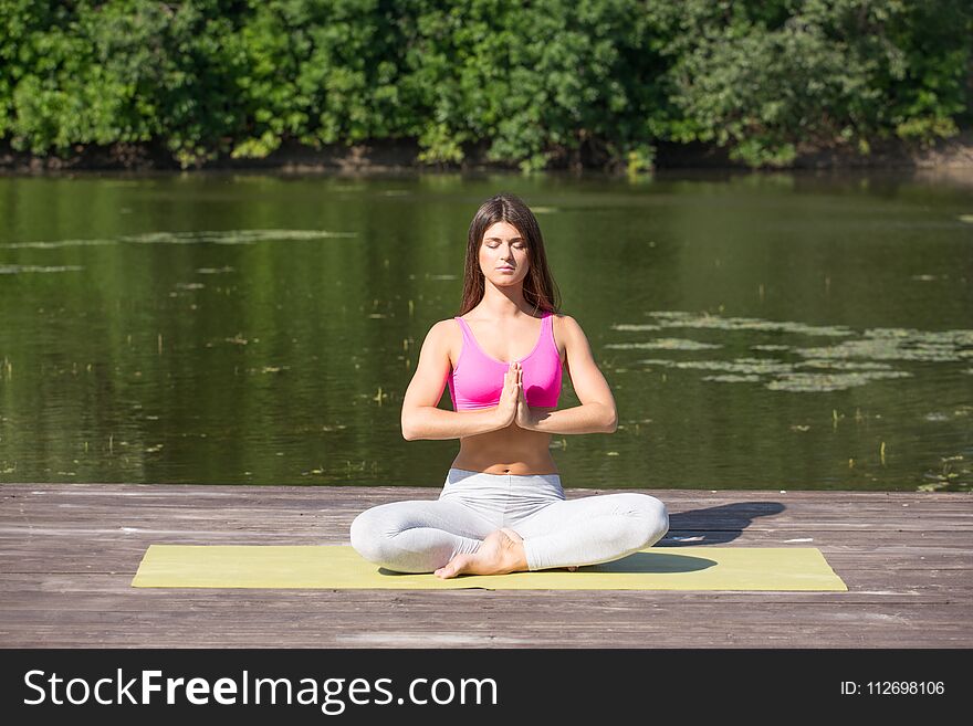 Young Girl Practices Yoga On The Shore Of The Lake, The Concept Of Enjoying Privacy And Concentration, Sunlight