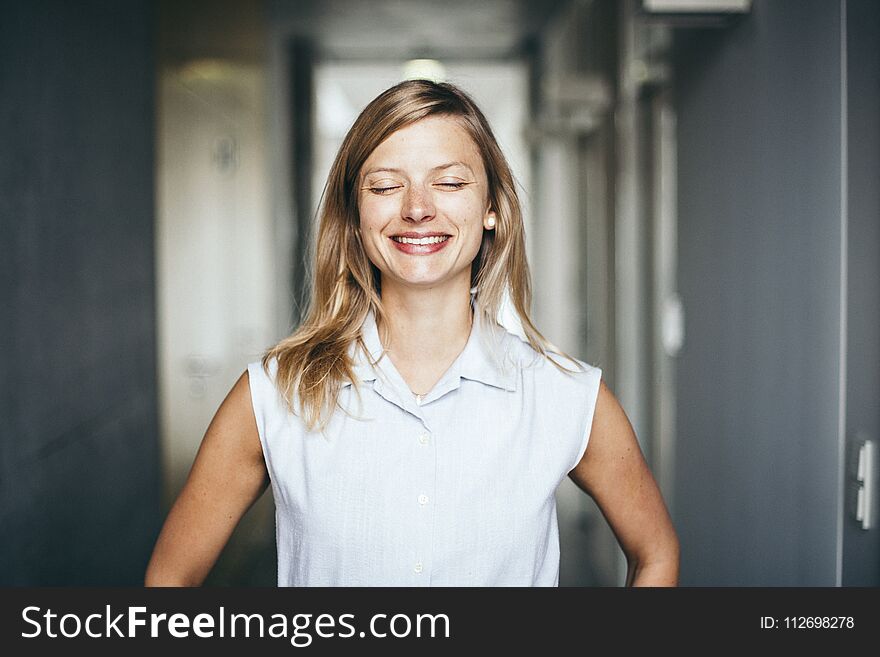 Blonde authentic and confident businesswoman with closed eyes in office hallway. Blonde authentic and confident businesswoman with closed eyes in office hallway
