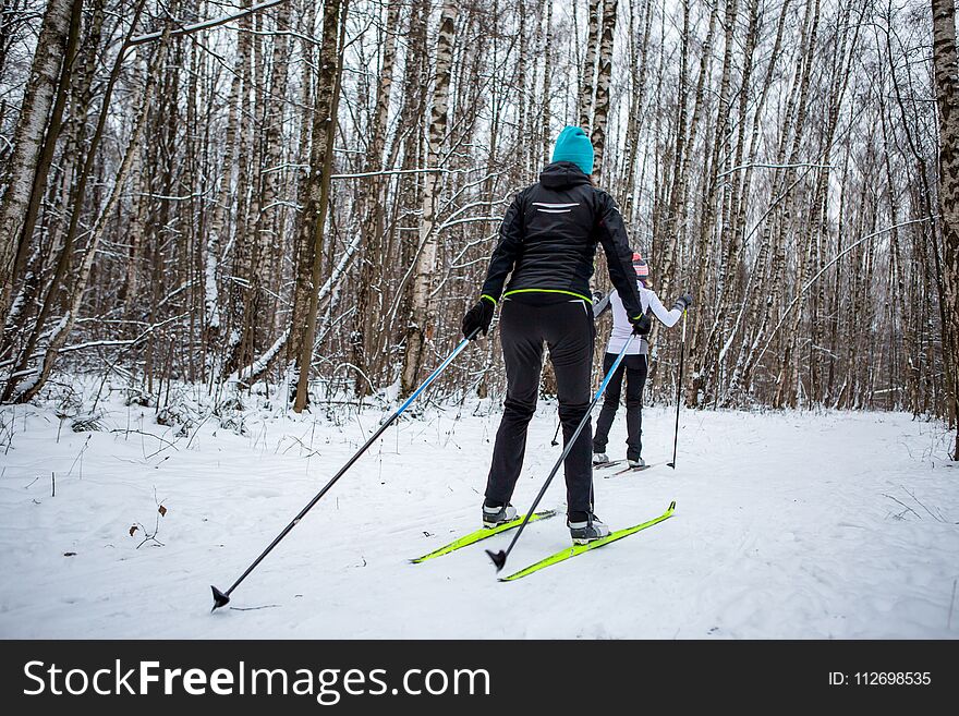 Picture of sports women and men skiing in winter forest during day