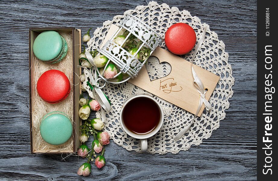 Macaroons in the box with decorations and a cup of tea