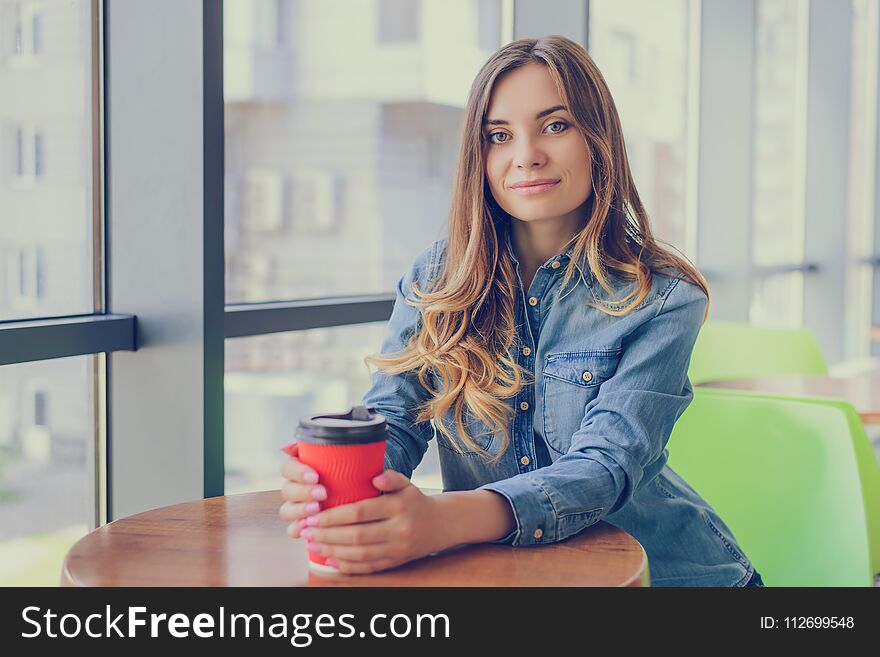 Portrait of gorgeous smiling young woman drinking takeaway coffee. She is having a break at work.