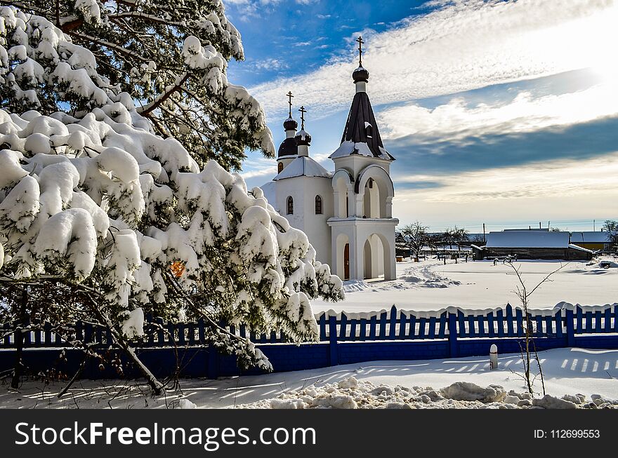 Church in winter in clear weather, a branch of conifer in the foreground. Church in winter in clear weather, a branch of conifer in the foreground