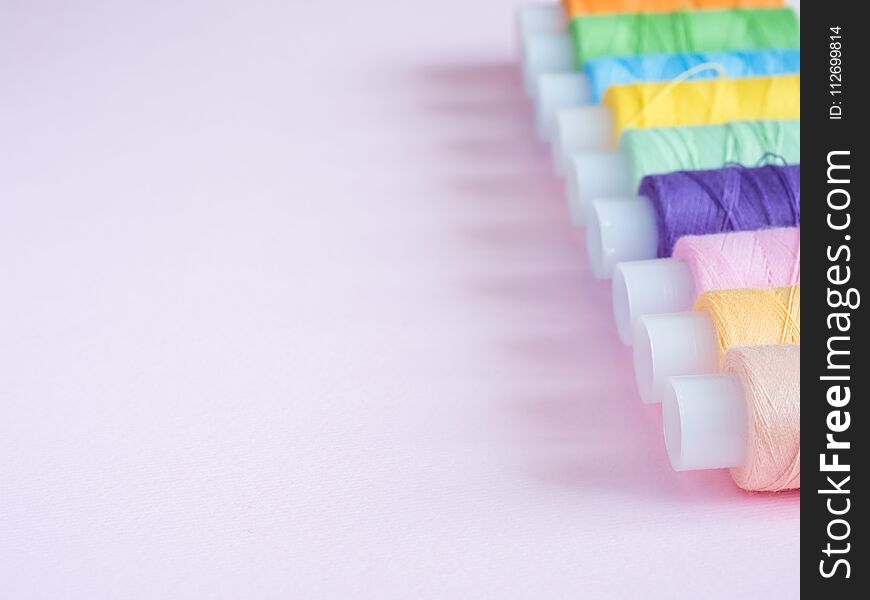 Colorful Sewing Buttons And Thread On A Pink Background.