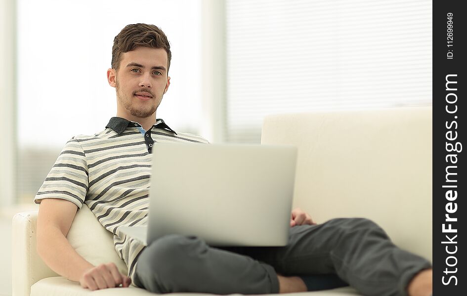 Happy man with laptop sitting on the couch. photo with copy space.