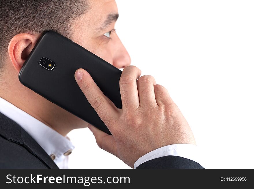 Portrait of serious young attractive man in black suit talking on mobile phone, isolated on white background.