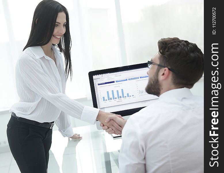 Employees greet each other with a handshake near the desk. Photo with blank space for text.