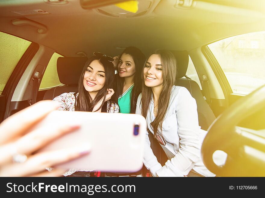 Capturing fun. Top view of three beautiful young women enjoying road trip in convertible and making selfie. Capturing fun. Top view of three beautiful young women enjoying road trip in convertible and making selfie