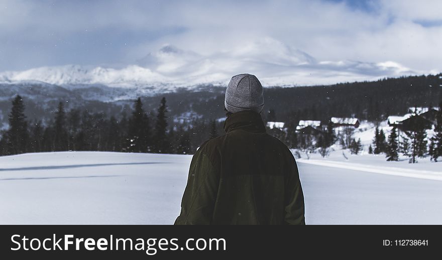 Man With Black Jacket And Grey Knit Cap Standing On White Snow Field