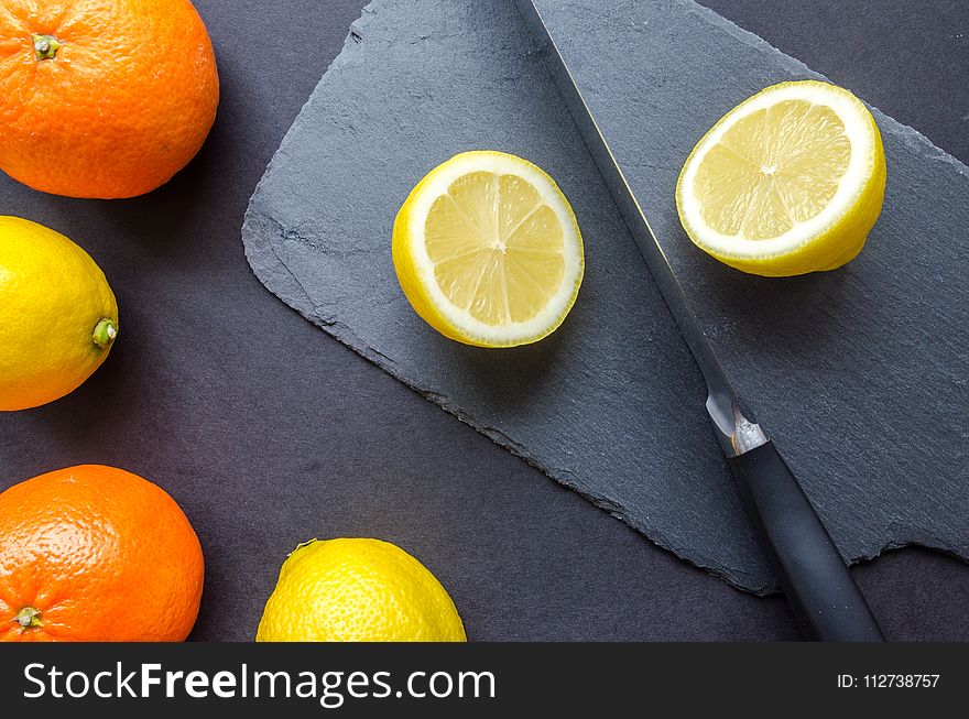 Two Orange and Three Lemons on Gray Surface