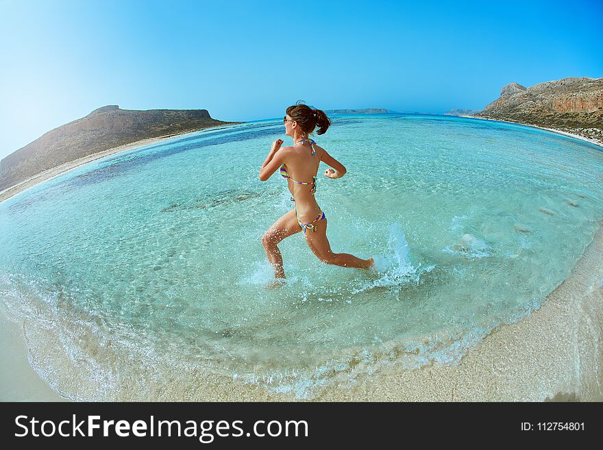 Beautiful athletic woman dressed in bikini running on the beach along the sea front. vacation and travel photography concept, wide angle shot. Beautiful athletic woman dressed in bikini running on the beach along the sea front. vacation and travel photography concept, wide angle shot