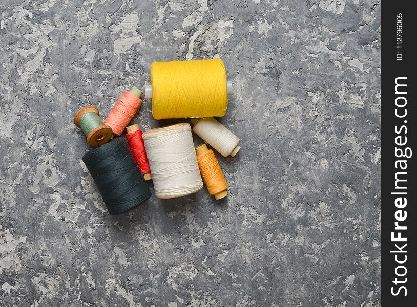 A group of multicolored skeins of thread on a gray concrete background. The concept of needlework. Made hand sewing clothes