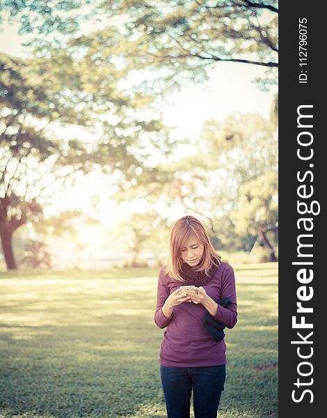 Woman standing in park writing text on smartphone At the park